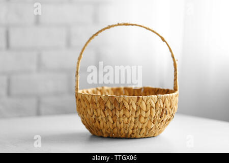Wicker basket with handle on wooden table, closeup Stock Photo