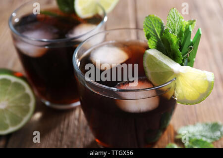 Two glasses of cola with ice, mint and lime on wooden table background Stock Photo