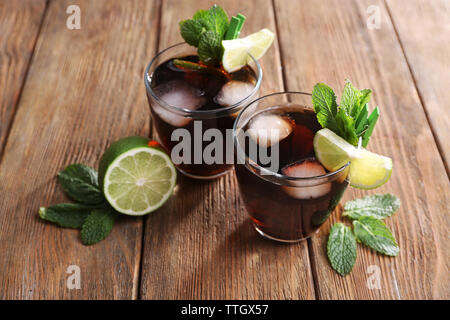 Two glasses of cola with ice, mint and lime on wooden table background Stock Photo