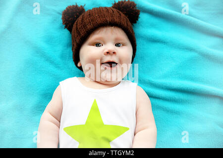 Little baby boy in knitted hat lying on the bed, close up Stock Photo