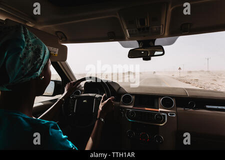 A woman drives an off-road vehicle on a road in the desert Stock Photo
