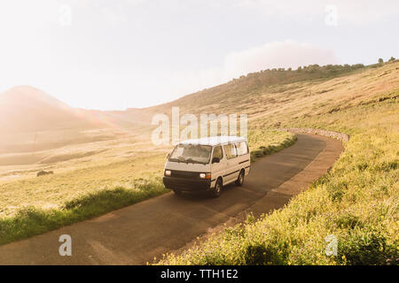Pulled back view of vintage van on empty road at sunset Stock Photo