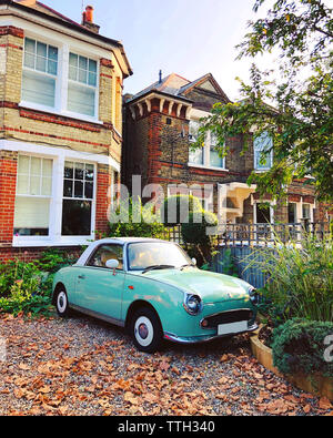 Old green car parked outside a house in autumn season Stock Photo
