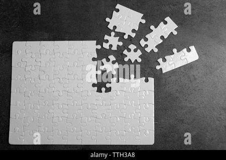 Unconnected white jigsaw puzzle with pieces on grey background Stock Photo