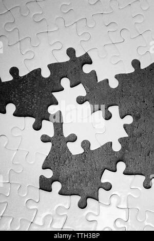 Unconnected white jigsaw puzzle with pieces on grey background Stock Photo