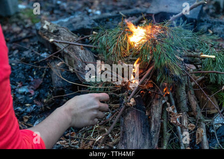 Woman starting a bonfire at a fireplace in the forest in autumn Stock Photo