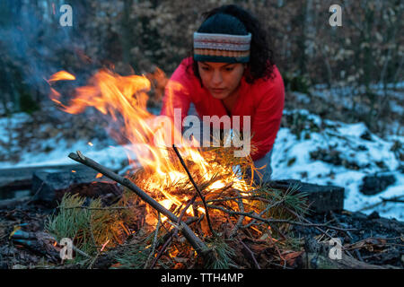 Woman starting a bonfire at a fireplace in the forest in autumn Stock Photo