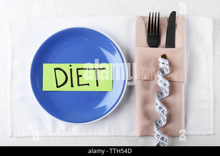 Piece of paper with word DIET in plate on wooden table with knife and fork, top view Stock Photo