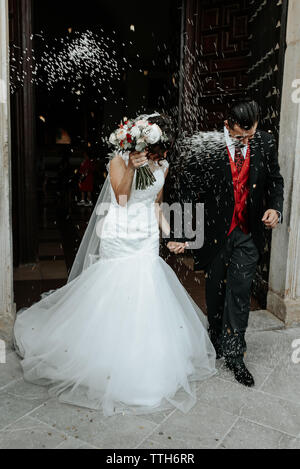 People throw rice on newlyweds walking out of the church Stock Photo