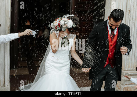 People throw rice on newlyweds walking out of the church Stock Photo