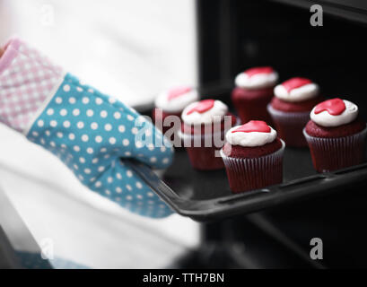 Woman baking chocolate cup cakes in glass tray in kitchen closeup. Young  girl put muffins in hot over. Female cooking tasty snack pastry at home.  Hea Stock Photo - Alamy