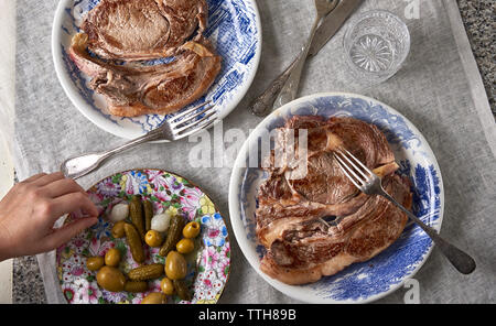 Hand picking an olive and steak with salada. Stock Photo