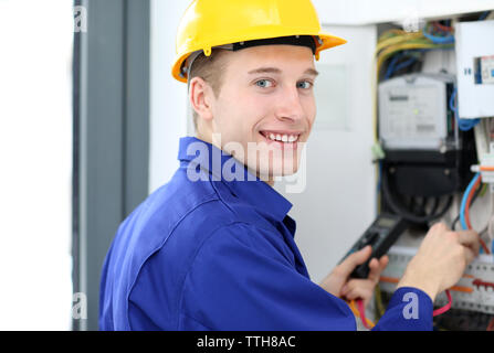 Young electrician measuring voltage in fuse board Stock Photo