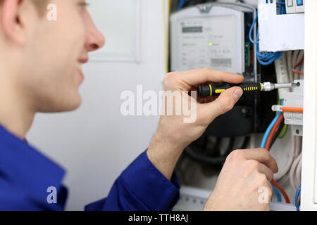 Young electrician working with screwdriver in fuse board Stock Photo