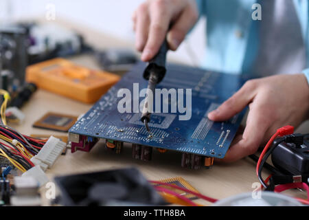 Young man working with soldering iron in service center Stock Photo