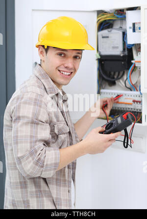 Young electrician measuring voltage in fuse board Stock Photo
