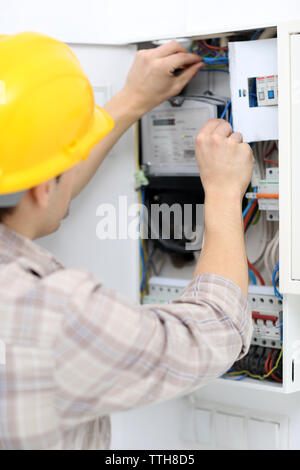 Young electrician checking voltage in fuse board Stock Photo