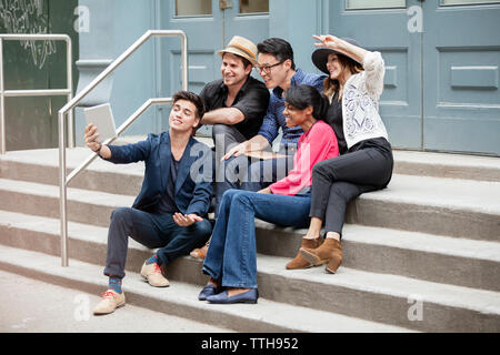Creative business people taking selfie while sitting on steps Stock Photo