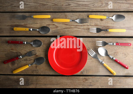 Plate and colorful flatware on wooden table, top view Stock Photo