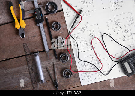 Digital multimeter and blueprint on a wooden background. Stock Photo