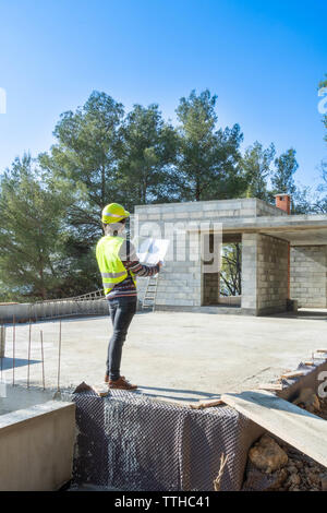 Architect checking the plans of a house under construction Stock Photo