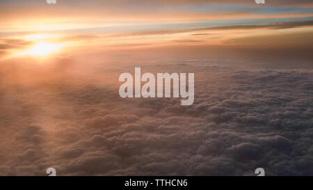 Aerial traveling. Wonderful view of the sky and clouds with the twilight from above, as seen through an airplane window. Morning mist. Flying at dusk Stock Photo