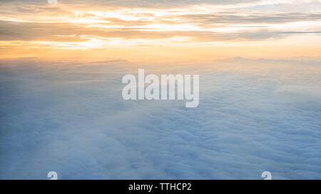 Aerial traveling. Wonderful view of the sky and clouds with the twilight from above, as seen through an airplane window. Morning mist. Flying at dusk Stock Photo