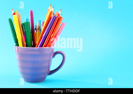 Colorful stationery in cup on blue background Stock Photo