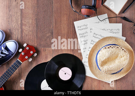 Small guitar, headphones, vinyl records and music sheets on wooden surface, top view Stock Photo