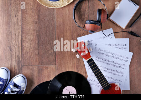 Small guitar, headphones, vinyl records and music sheets on wooden surface, top view Stock Photo