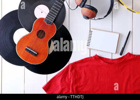 Musical equipment and clothes on wooden surface, top view Stock Photo