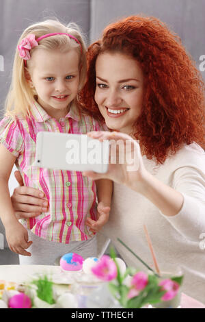 Mother and daughter making selfie while decorating Easter eggs, indoors Stock Photo