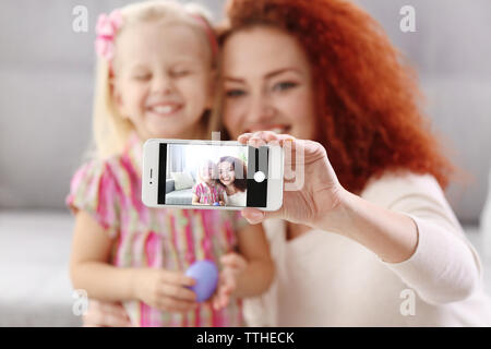 Mother and daughter making selfie while decorating Easter eggs, indoors Stock Photo