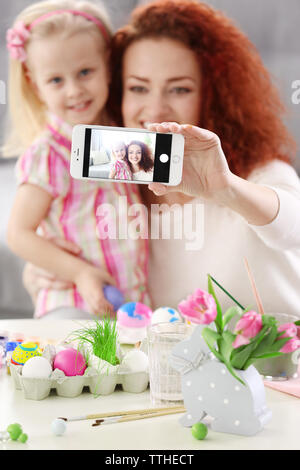 Mother and daughter making selfie while decorating Easter eggs, indoors Stock Photo