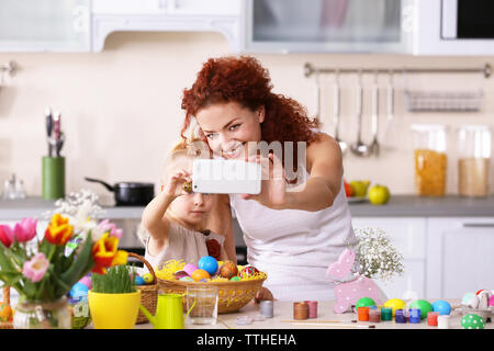 Mother and daughter making selfie while decorating Easter eggs in the kitchen Stock Photo