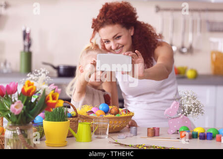 Mother and daughter making selfie while decorating Easter eggs in the kitchen Stock Photo