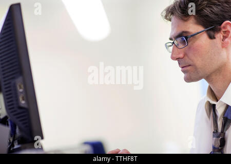 Side view of serious dentist using computer at clinic Stock Photo