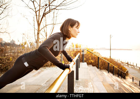 Woman doing push-ups on railing Stock Photo