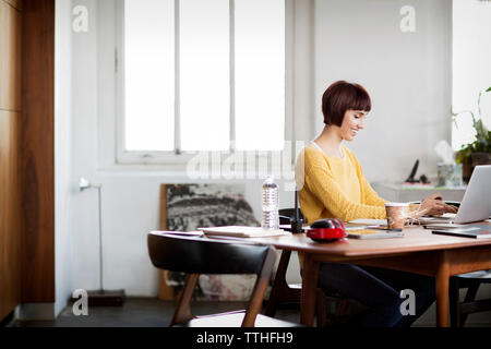 Happy photo editor using laptop at table in creative office Stock Photo