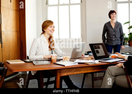 Happy businesswomen having discussion at conference table in meeting Stock Photo