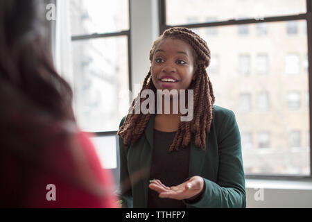 businesswoman talking to colleague while standing in office Stock Photo