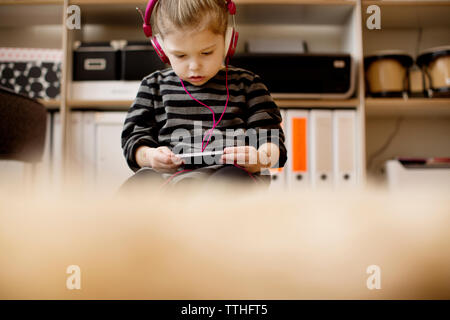 Girl listening to music while using phone at home Stock Photo