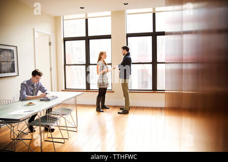 businessman using phone while colleagues having discussion in background Stock Photo