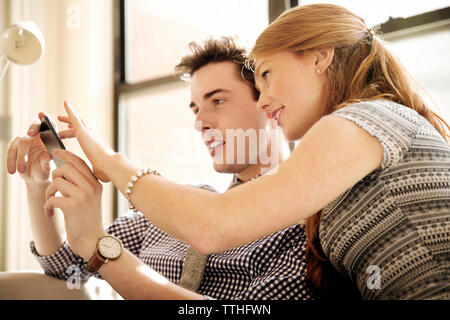 Colleagues using phone while sitting in office Stock Photo