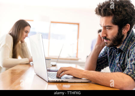 Man and woman using laptop while sitting at table Stock Photo