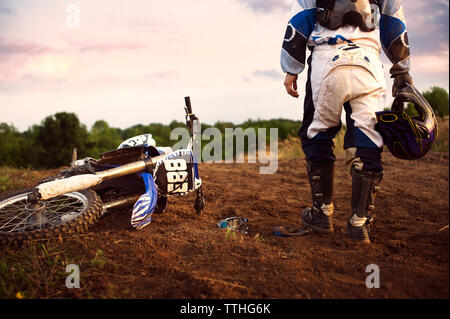 Low section of dirt biker standing on field Stock Photo