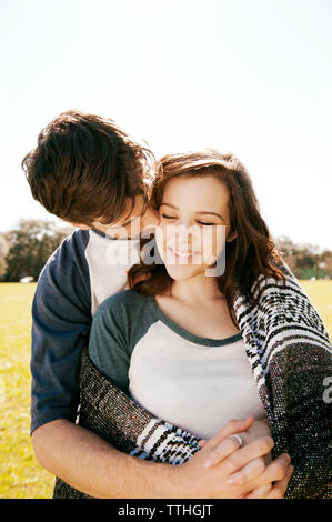 Man embracing girlfriend while kissing at park Stock Photo