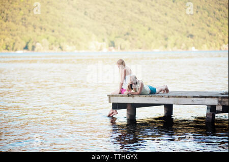 Females resting on jetty over lake Stock Photo