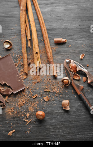 Pieces of chocolate with hazelnuts, cracker and cinnamon on black wooden background Stock Photo