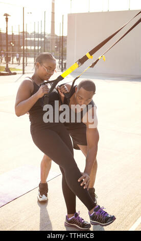 Coach helping sportswoman in performing exercise Stock Photo